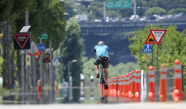 서울 송파구 한강공원을 찾은 시민이 지열로 아지랑이가 피어오르는 자전거도로를 지나고 있다. / 사진=연합뉴스 제공