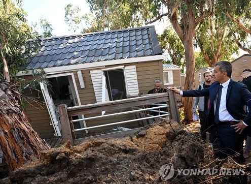 France's Interior Minister Gerald Darmanin (R) looks at a damaged bungalow at La Pinede camping site in Calvi in the French Mediterranean island of Corsica, on August 19, 2022, during his second-day visit one day after brutal storms with winds gusting up to 224 kilometres per hour (140 miles per hour) left five people dead, including a 13-year-old girl. - It was the third day of intense rains across much of southern France that had produced flash floods and lightning, but left no casualties until now. (Photo by Emmanuel DUNAND / POOL / AFP)