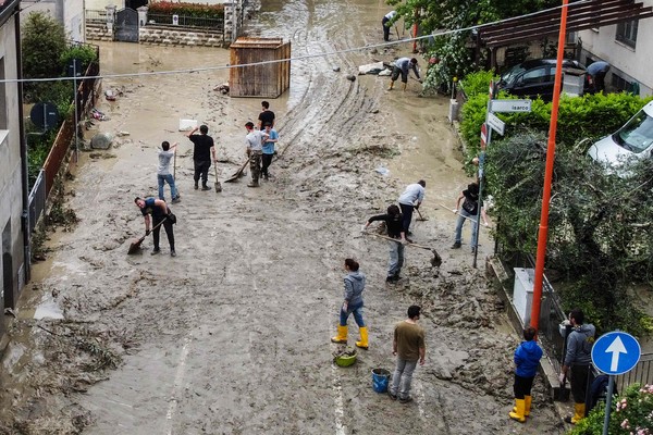 사진=주민들이 홍수가 지나간 도로를 청소하고 있다./AFP, 연합뉴스 제공