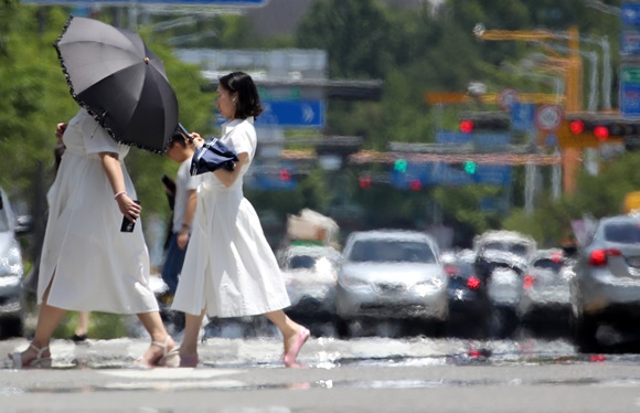 사진 = 15일 오후 광주 서구 내방로에서 시민들이 뜨거운 햇볕에 달아올라 아지랑이가 피어오르는 도로를 건너고 있다 / 연합뉴스
