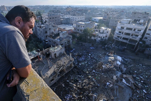 A Palestinian man looks a building destroyed in an Israeli airstrike in the Rafah refugee camp in the southern of Gaza Strip, on October 16, 2023. Israel declared war on the Islamist group Hamas on October 8, a day after waves of its fighters broke through the heavily fortified border and killed more than 1,400 people, most of them civilians. The relentless Israeli bombings since have flattened neighbourhoods and left at least 2,670 people dead in the Gaza Strip, the majority ordinary Palestinians. (Photo by MOHAMMED ABED / AFP)