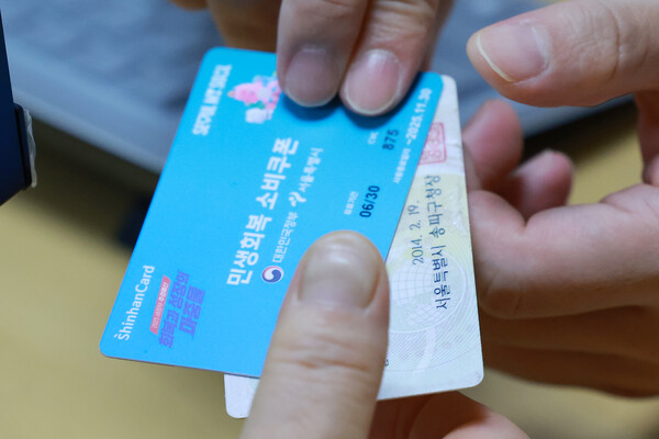 민생회복 소비쿠폰 신청이 시작된 지난 21일 서울 송파구 거여2동주민센터에서 시민이 신청한 소비쿠폰을 받고 있다.