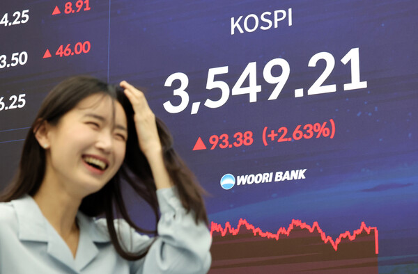 코스피가 사상 처음 3,500선을 돌파하며 종가 기준 역대 최고치인 3549.21로 마감한 2일 오후 서울 중구 우리은행 딜링룸에서 한 여성이 환하게 웃고 있다. 연합뉴스